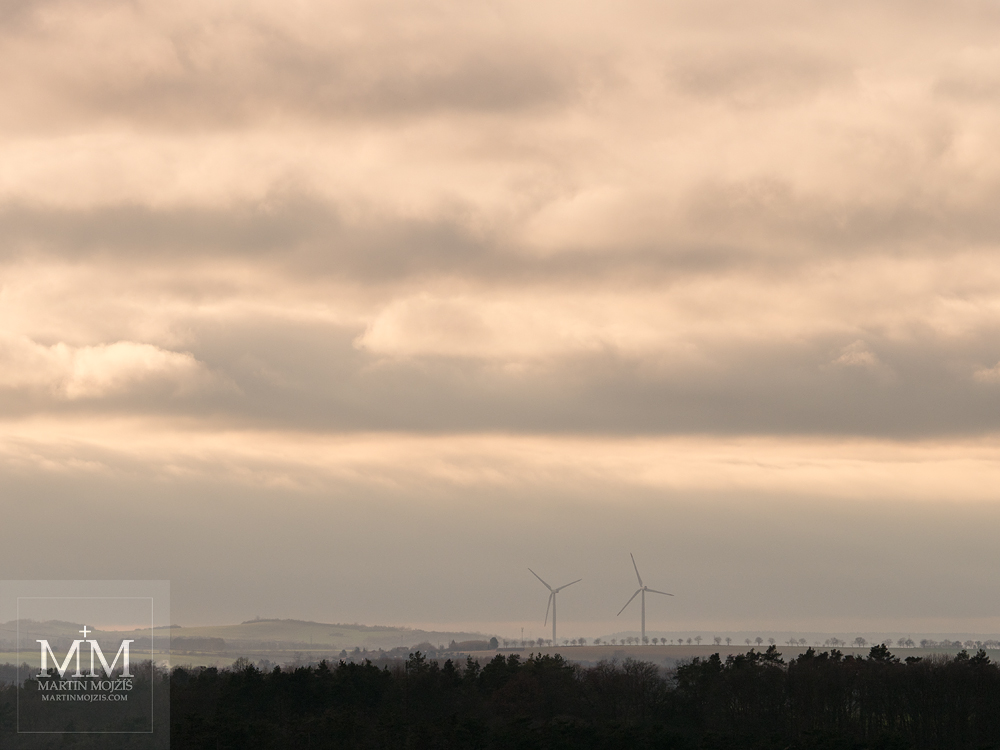 Mraky nad krajinou, dvě větrné elektrárny. Fotografie vytvořená objektivem Olympus M. Zuiko digital ED 40 - 150 mm 1:2.8 PRO.